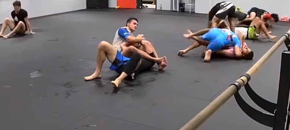 Adults drilling no-gi jiu-jitsu positions on the studio mat floor.