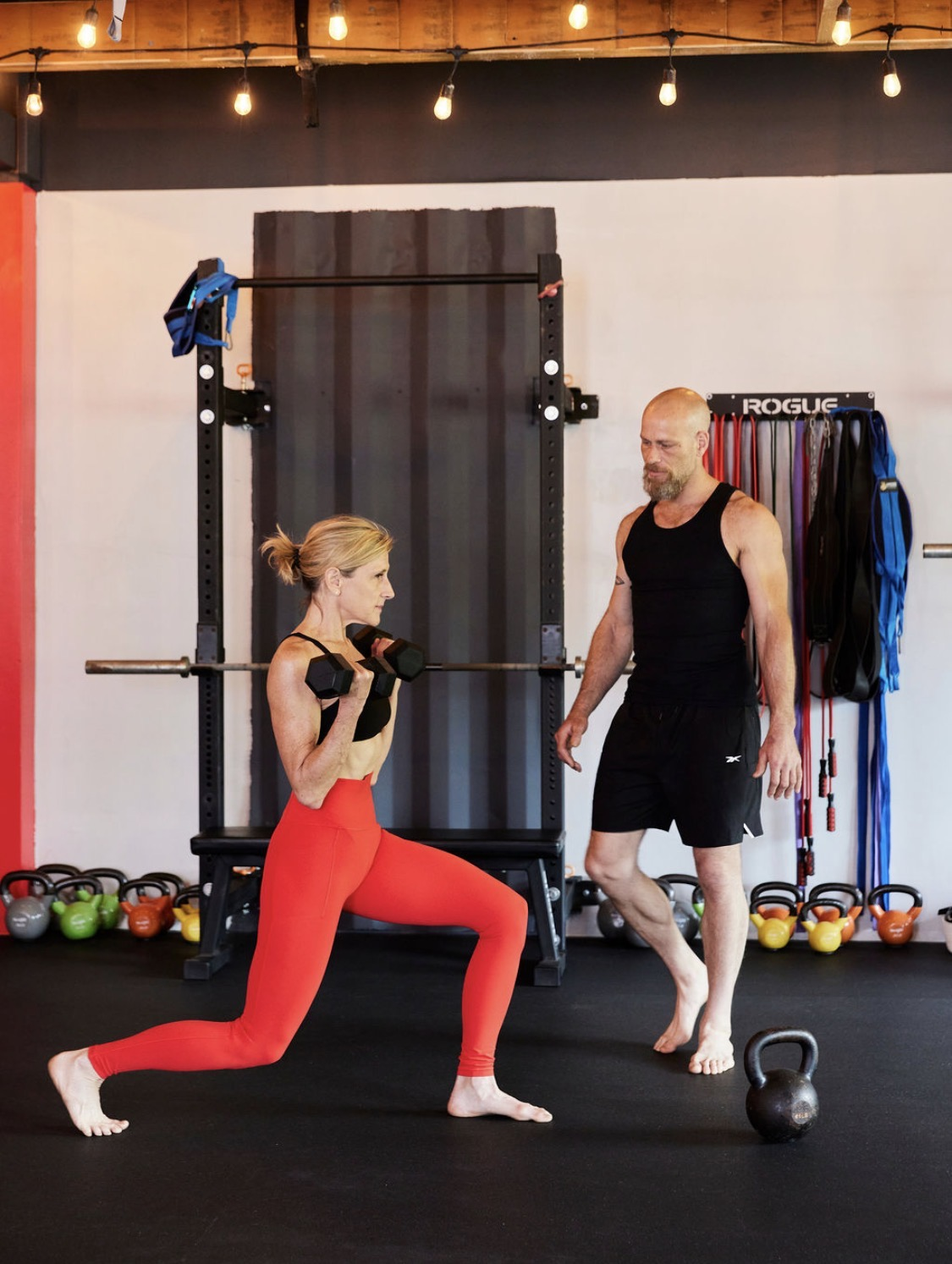 Coach guiding a client through a dumbbell lunge during a private training session.